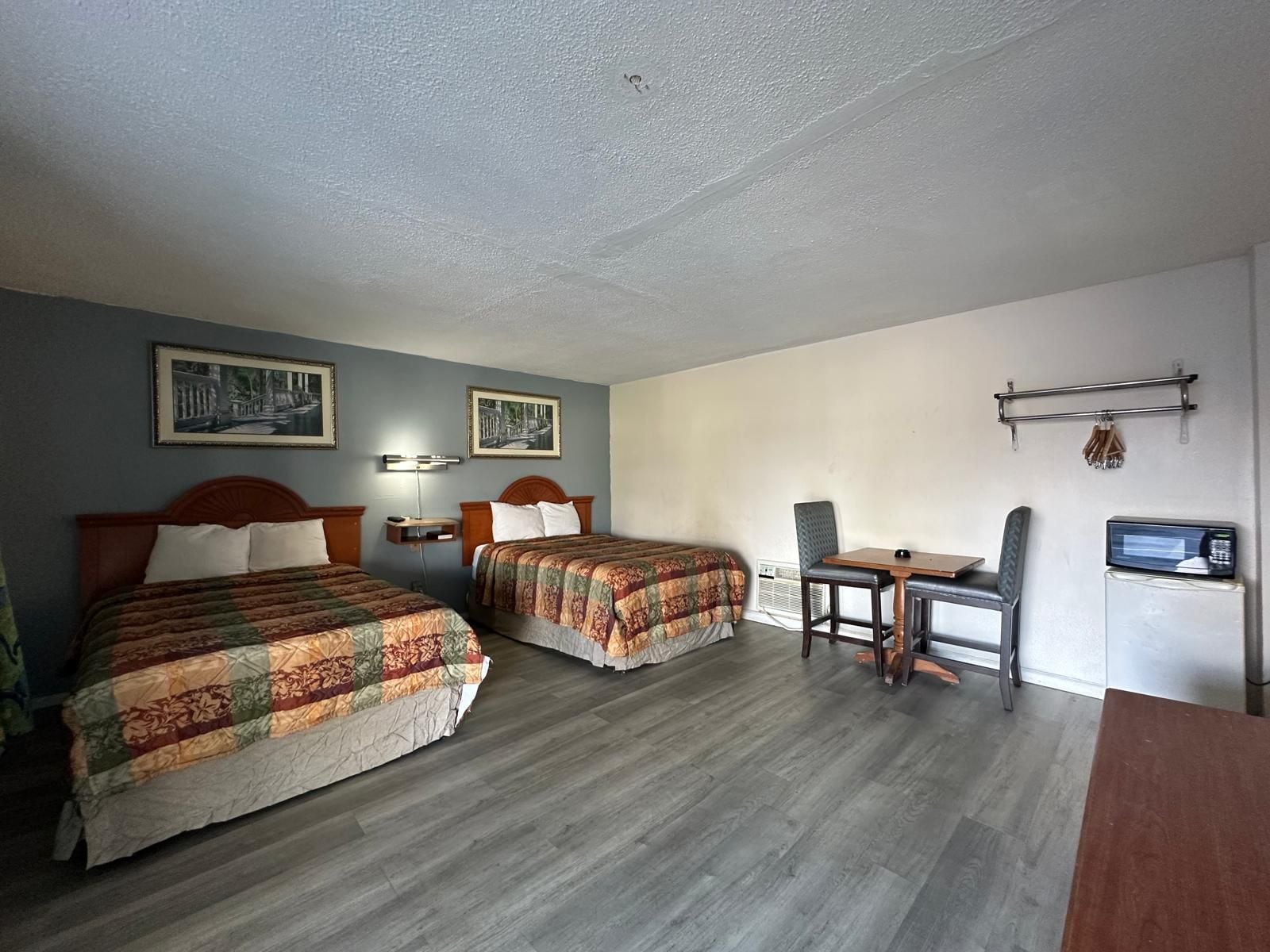 Habitación de hotel con dos camas, un escritorio, una silla, un televisor y dos lámparas fijadas a la pared.
