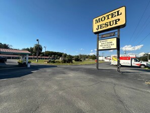 Ein Motel namens 'Motel Jesusup' mit einem Schild, das HBO-Filme, Playboy, hochwertige Zimmer, kostenlosen Kaffee, WLAN und die besten Preise bewirbt.