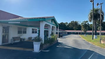 A motel with a covered parking area, a bench, and a sign indicating a clearance of 7'6'.