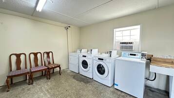 A laundry room with a washing machine, dryer, and a wooden chair.