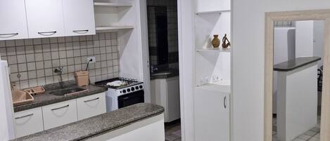 A compact kitchen with white cabinets, a granite countertop, and a tiled backsplash.