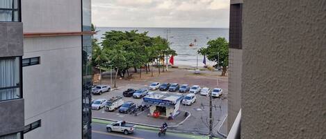A view from a balcony overlooking a parking lot with a body of water in the background.