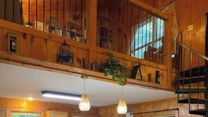 Una cocina amplia con armarios de madera, una isla central con taburetes de bar y una escalera que sube a un nivel superior.