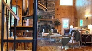 Un interior de madera con una escalera de caracol, chimenea de piedra y pisos de madera.
