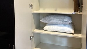 Un armario blanco con varios estantes, una barra para colgar y un perchero.