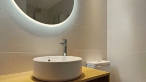 Een moderne badkamer met een rond wastafel, een spiegel en een toilet.