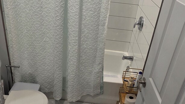 Un baño con cortina de ducha, inodoro y un lavabo pequeño.