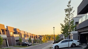Una calle residencial moderna con acera pavimentada, coches aparcados y cielo despejado.