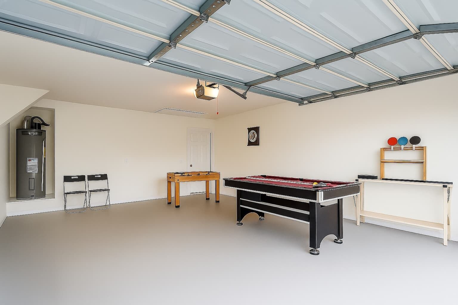 Une pièce spacieuse équipée d’un baby-foot, d’une table de ping-pong et d’une petite table avec des chaises.
