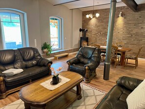A cozy living room with leather sofas, a wooden coffee table, and a fireplace. - Family-friendly, spacious vacation apartment in a quiet, rural location (Bliesdorf)