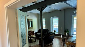 Ein geräumiges Wohnzimmer mit einer schwarzen Ledersofa, einem Holzesstisch und einem großen Fenster, das für natürliches Licht sorgt.