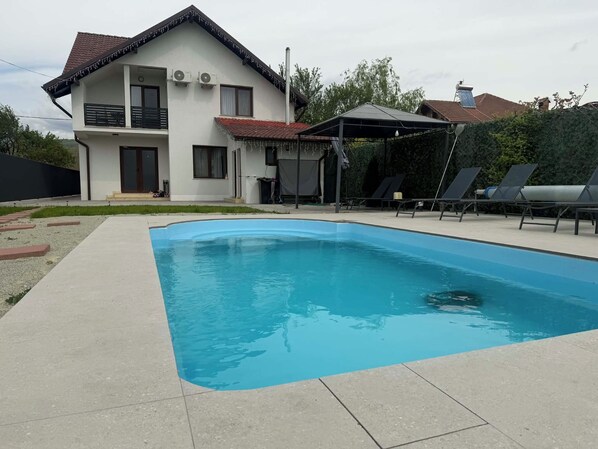 A modern house with a swimming pool, a covered patio, and a garden. - Casuta de pe Ses (Novaci)