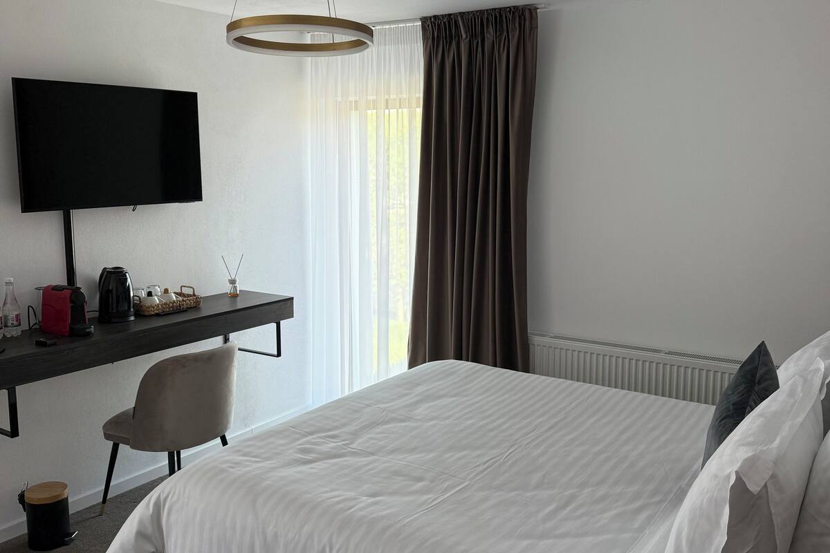 Een hotelkamer met een bed, een bureau met een flatscreen televisie, een stoel, een koffiezetapparaat en een radiator.