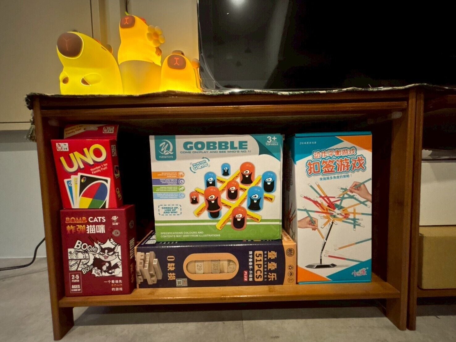 Una estantería con varios juegos de mesa, incluyendo UNO, GOBBLE y un juego con temática de gato.
