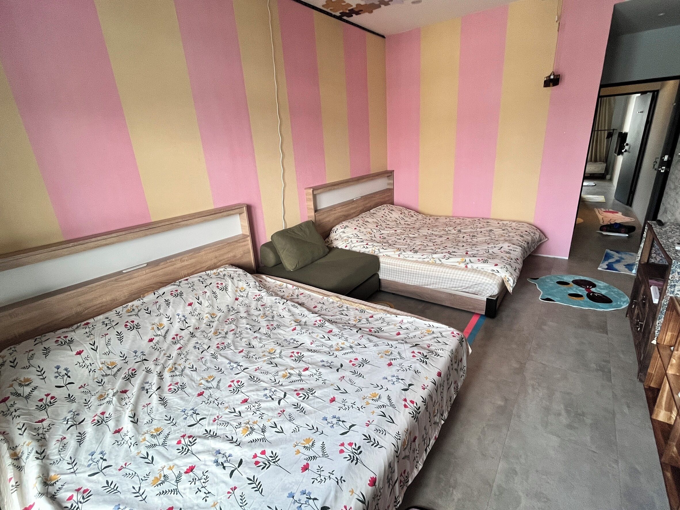 A bedroom with two single beds, a wooden headboard, and a pink and beige striped wall.