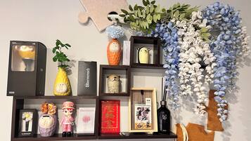 A shelf with various decorative items including a puzzle piece, artificial flowers, figurines, a framed photo, and a bottle.
