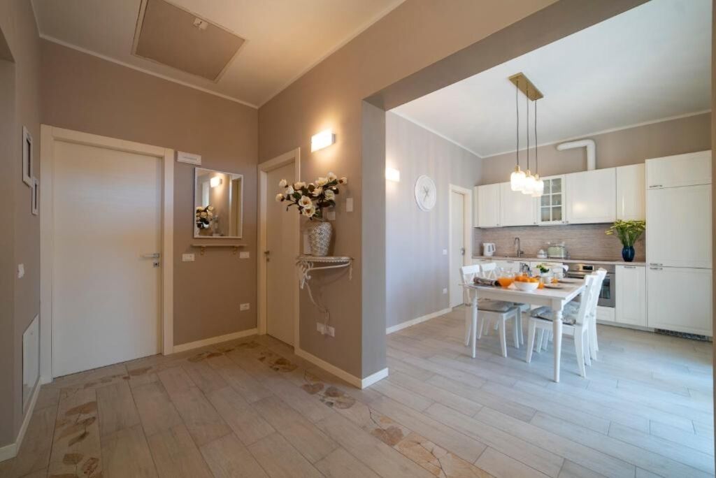 A modern kitchen with white cabinets, a dining table, and a hanging light fixture.