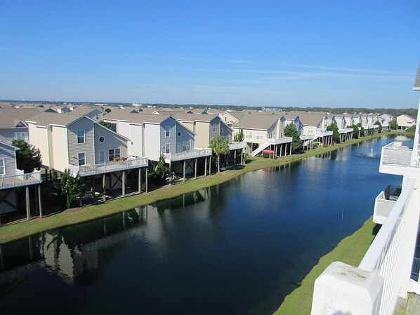 A row of modern houses with a canal in the foreground. - 4 Bed Islander Villas / Elevator/ Access to Oceanfront Pool! (Ocean Isle Beach)