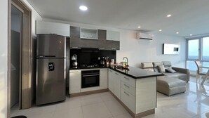 Una cucina moderna con forno integrato, un frigorifero spazioso e un'area pranzo con divano e tavolo.
