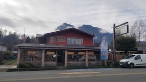 A hotel with a red facade, a balcony, and a mountain backdrop. - Hotel Elizabeth (Panguipulli)