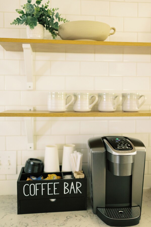 Un bar à café équipé d’une machine à café, de tasses et d’un récipient pour les grains de café.