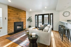 Ein Wohnzimmer mit Kamin, einer Couch, einem Couchtisch und einer Wanduhr.