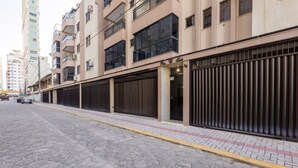 A multi-story building with a gated entrance, a paved sidewalk, and a cobblestone street. - Beachfront Apartment With Beach View Vte0301 (Itapema)