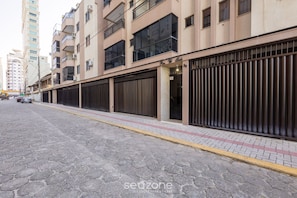 A multi-story building with a gated entrance, a paved sidewalk, and a cobblestone street. - Beachfront Apartment With Beach View Vte0301 (Itapema)