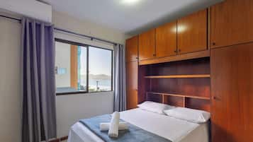 Quarto de hotel com cama, guarda-roupa de madeira e janela com cortinas.