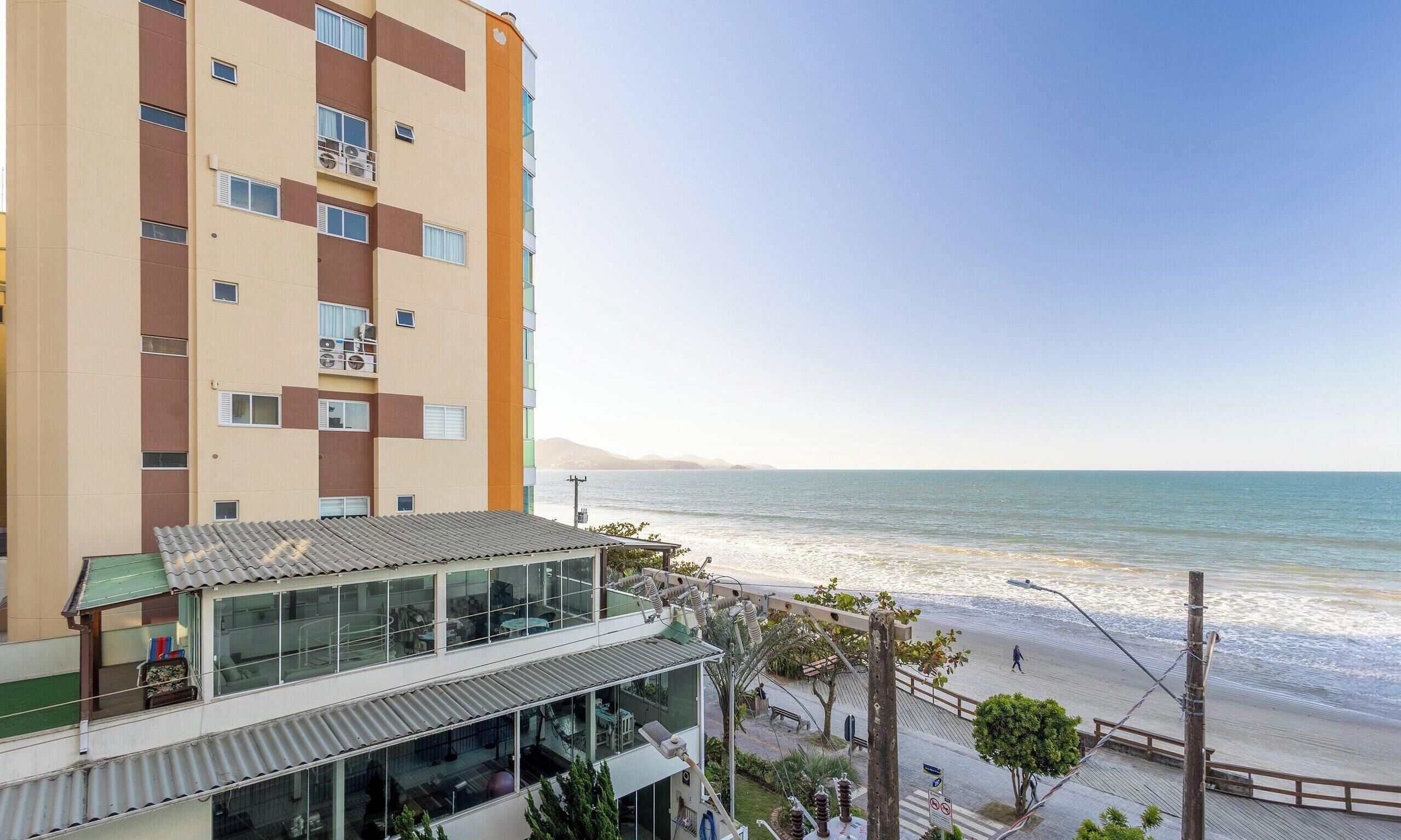 A multi-story building with balconies overlooking a beach.