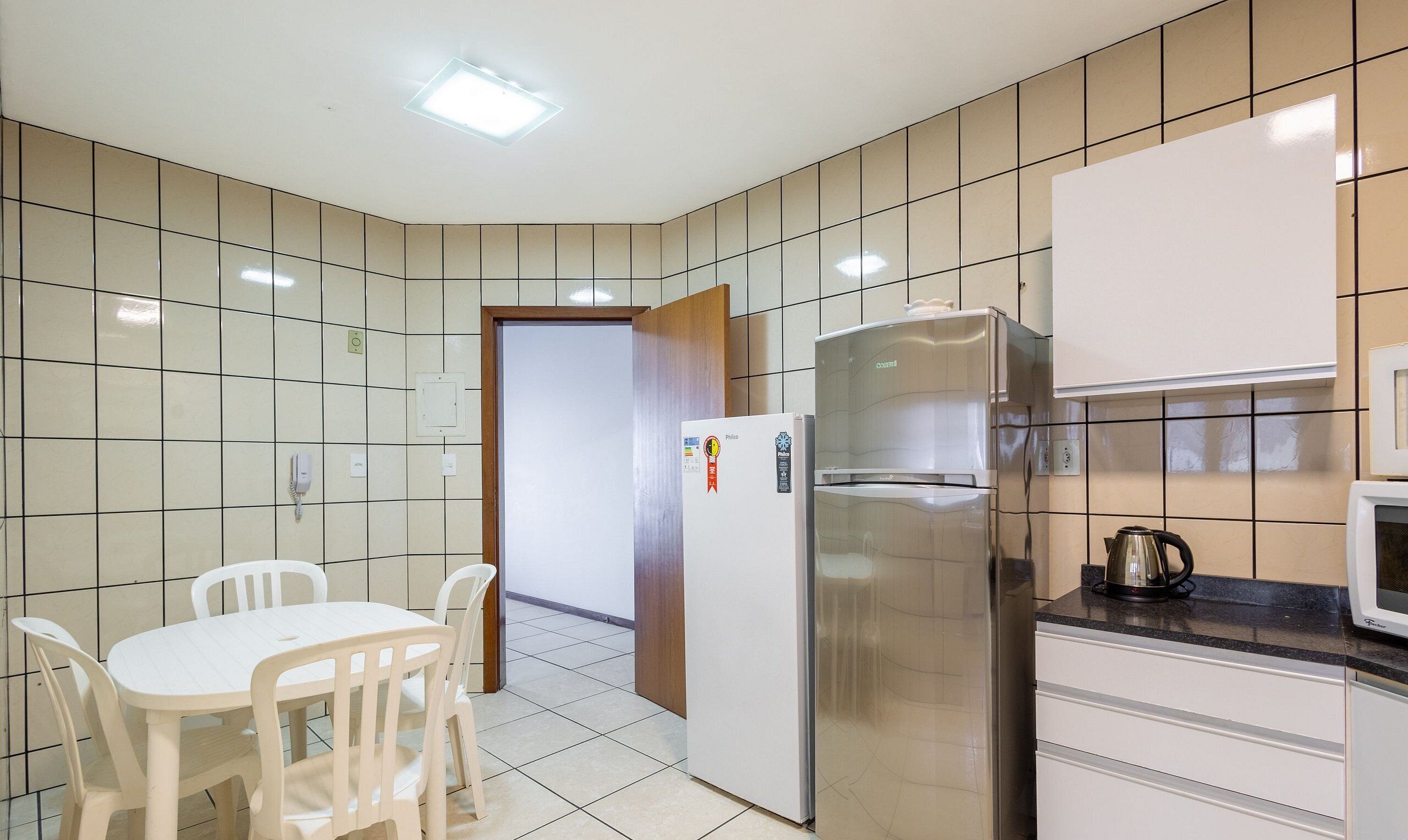 Eine Küche mit Kühlschrank, Mikrowelle und einem Tisch mit Stühlen.