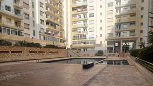 A residential building with multiple balconies, a swimming pool, and a stone wall.