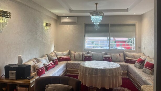A cozy living room with a sectional sofa, a round coffee table, and a chandelier.