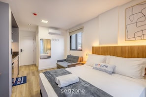 A modern hotel room with a bed, a seating area, a window, and a view of the outside. - New Studios - Pool With sea View - Penha Spot PSO (Penha)