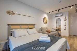 A modern hotel room with a bed, a sofa, a small table, and a mirror.