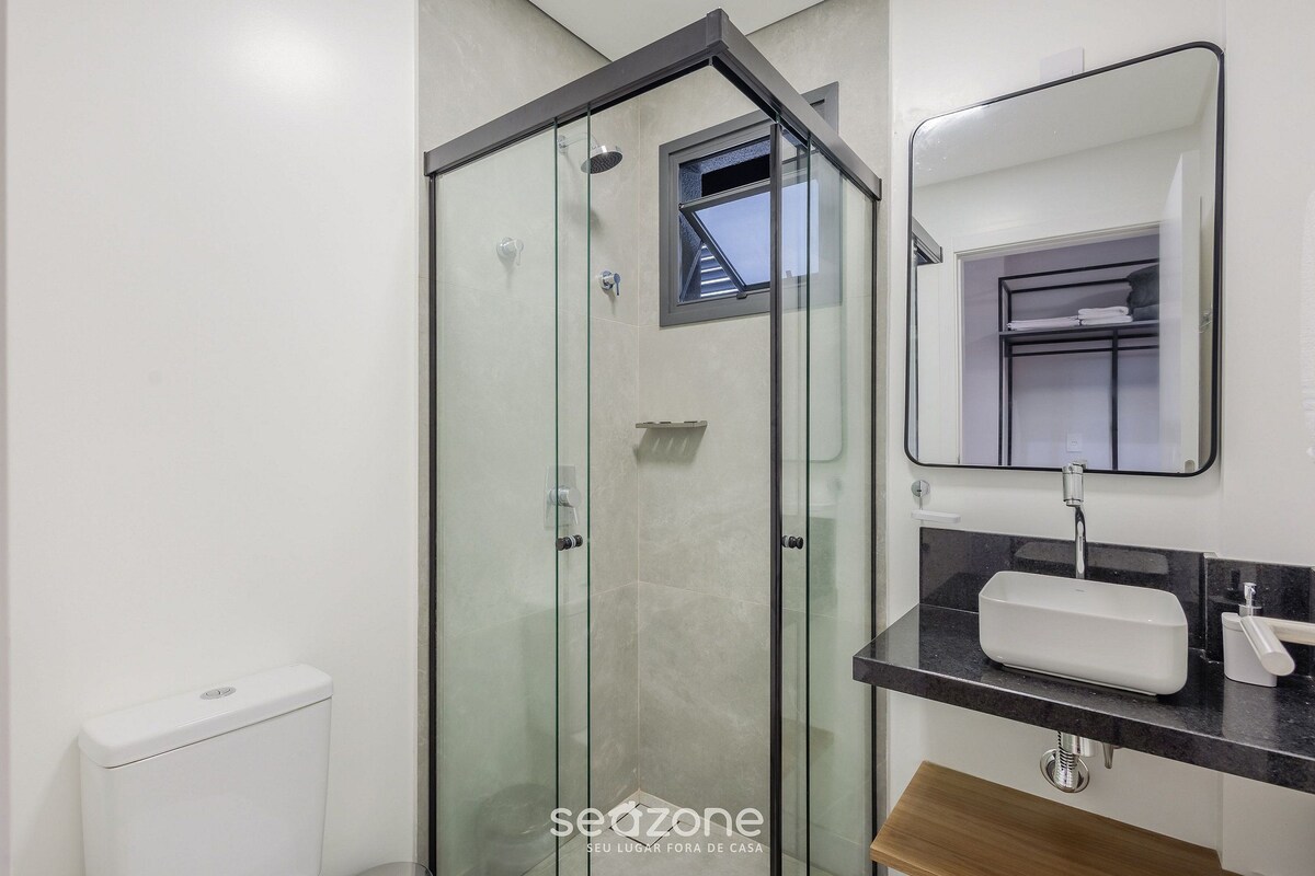 A modern bathroom with a glass-enclosed shower, a white sink, and a mirror above it.