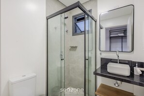 A modern bathroom with a glass-enclosed shower, a white sink, and a mirror above it.