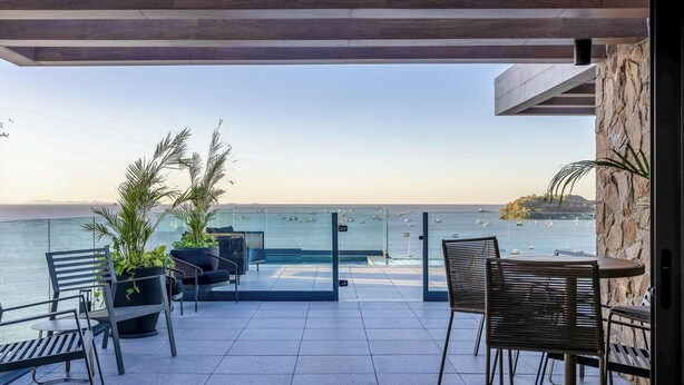 Eine Terrasse mit Sitzgelegenheiten, Meerblick und einer Steinmauer.