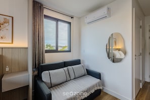 A modern living room with a sofa, a large window, an air conditioning unit, and a mirror on the wall. - New Studios - Pool With sea View - Penha Spot PSO (Penha)