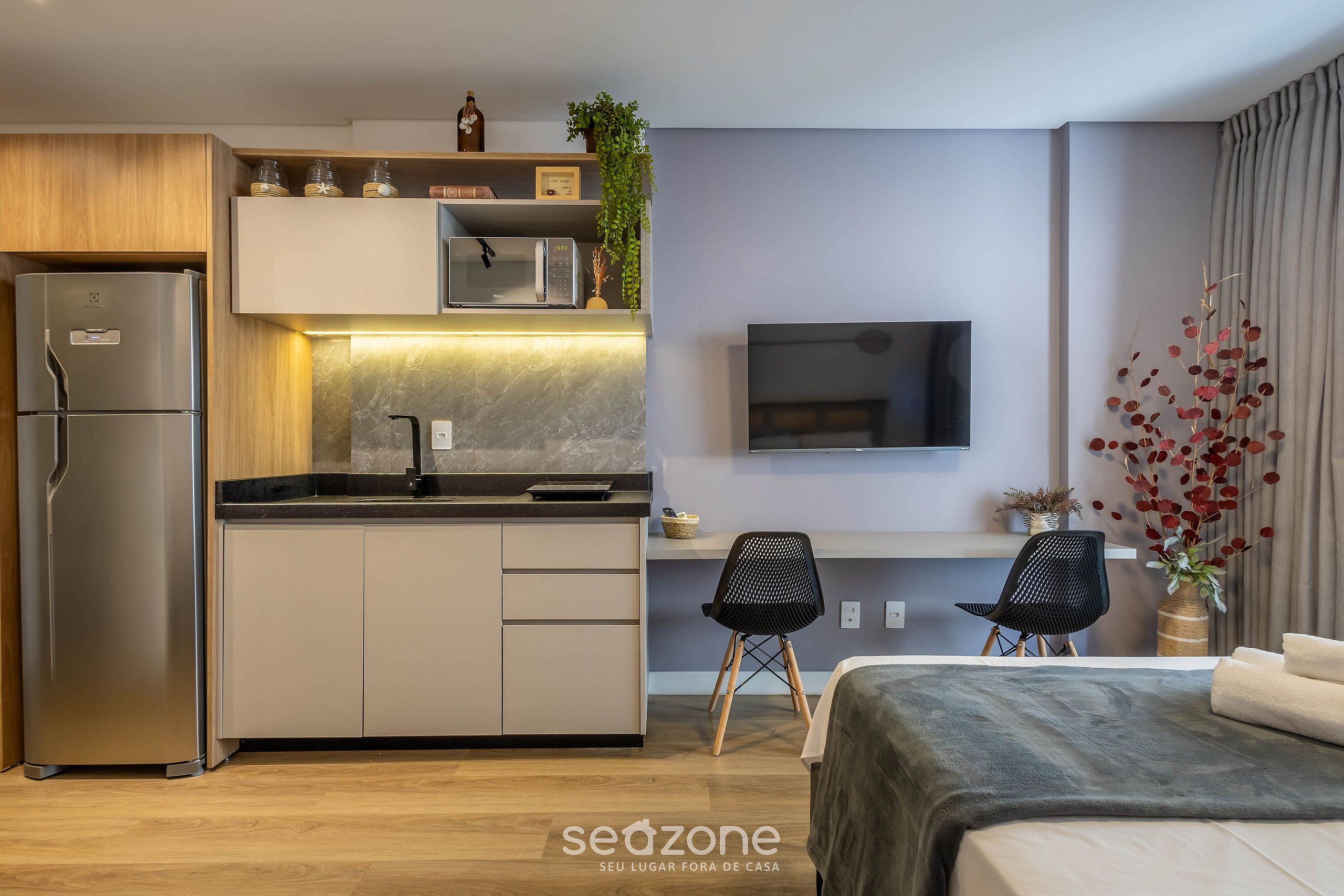 Una cocina moderna con microondas integrado, un refrigerador y un comedor con dos sillas.