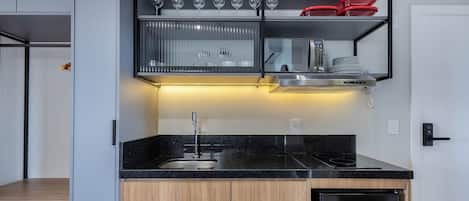 Eine moderne Küche mit schwarzem Arbeitsplatz, Edelstahlgeräten und einem eingebauten Weinkühlschrank.