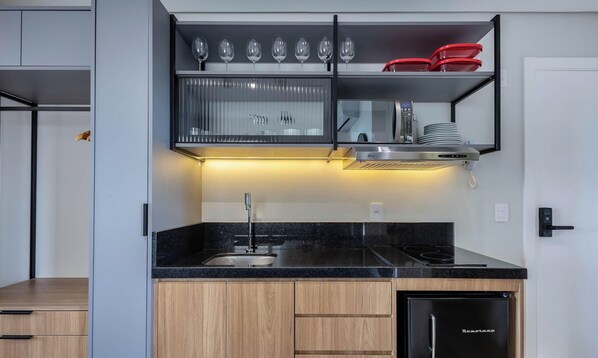 Une cuisine moderne dotée d’un plan de travail noir, d’appareils électroménagers en acier inoxydable et d’un meuble à vin intégré.