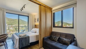 Ein Hotelzimmer mit Bett, Sofa, Blick auf Stadt und Berge sowie einem großen Fenster.