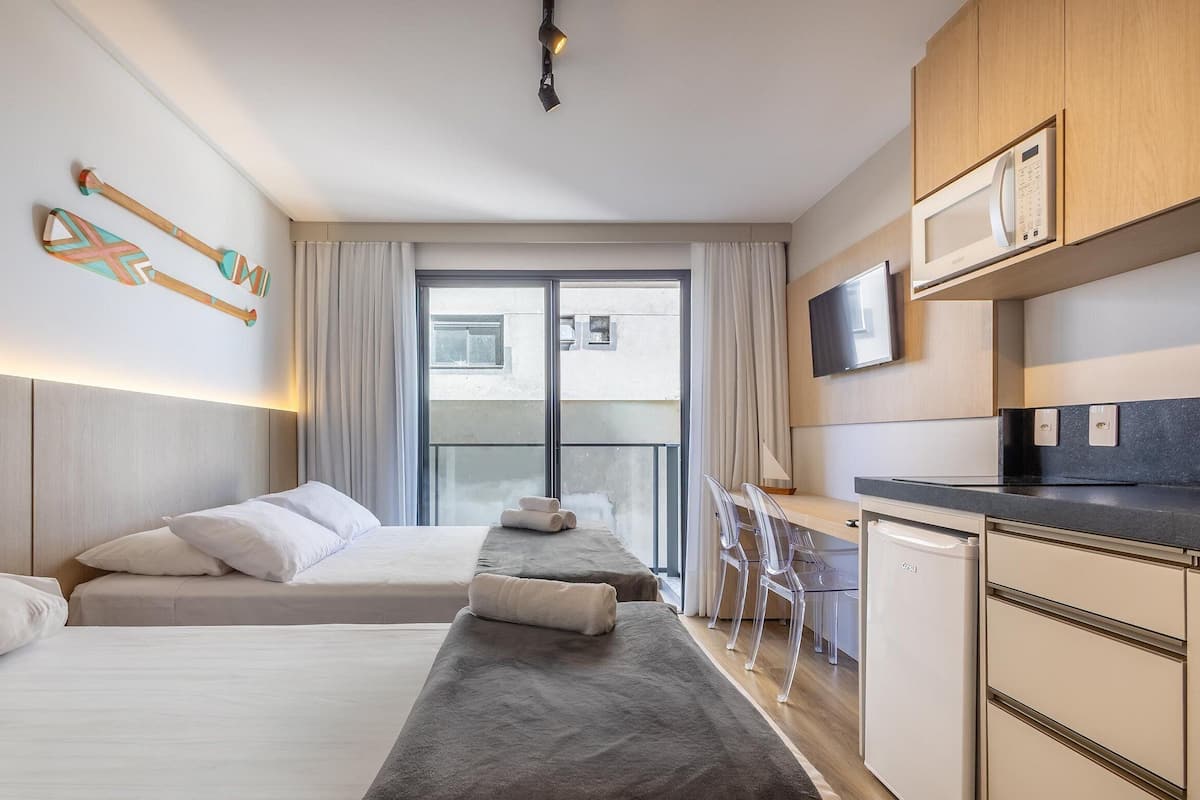A hotel room with two beds, a TV, a microwave, and a view of the city.