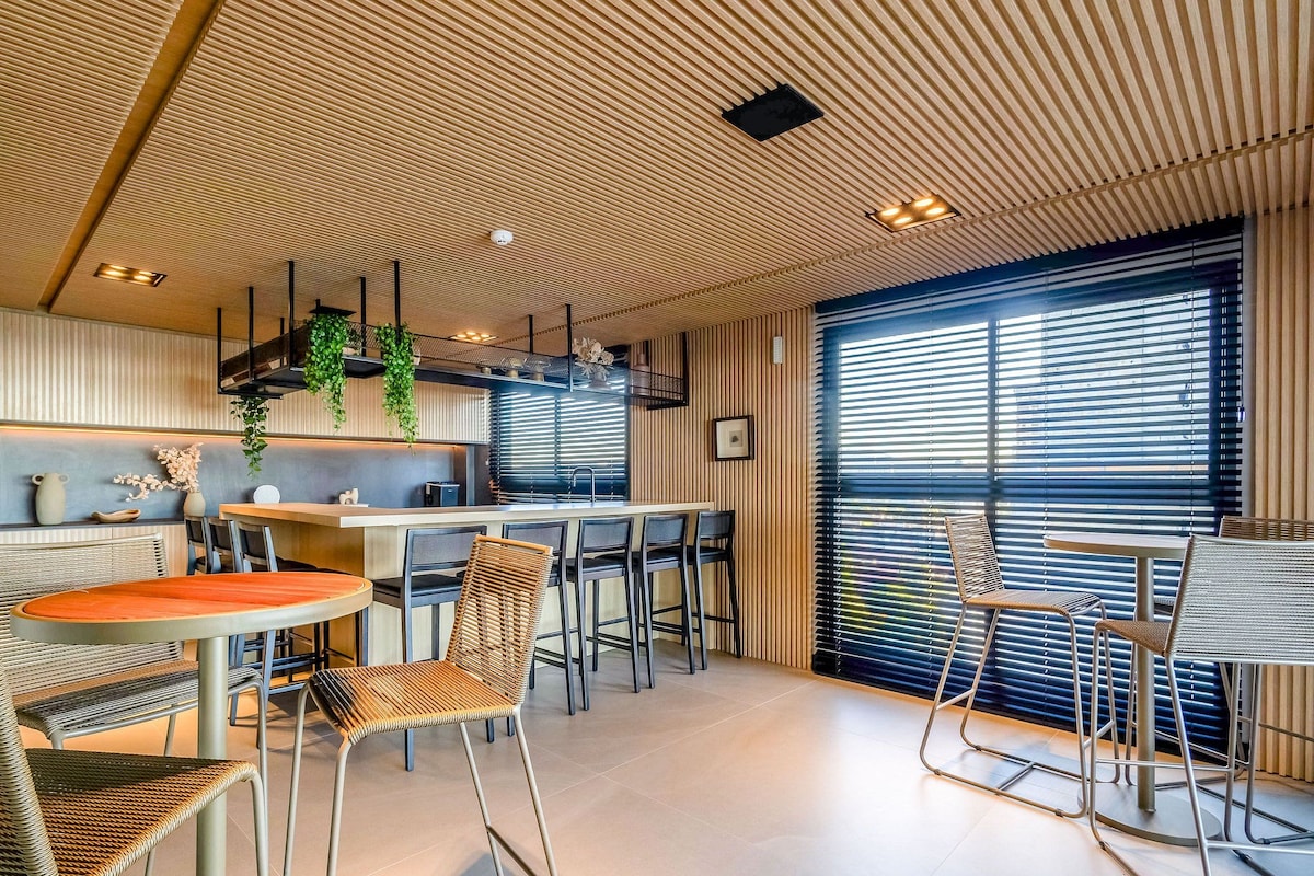 Un intérieur moderne comprenant une cuisine, un coin repas et de grandes fenêtres.