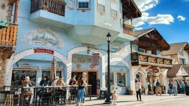 Un edificio tradicional con un balcón, un cartel de restaurante y una calle frente a él.