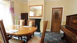 A dining room with a wooden table, chairs, a fireplace, and a mirror on the wall. - Cosyhaven - Holiday Home in Southbourne, Bournemouth - ideal for Family Holidays (Bornemouth)