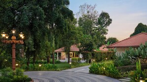Um jardim ajardinado com um caminho curvo que leva a um edifício com telhado de telhas vermelhas.