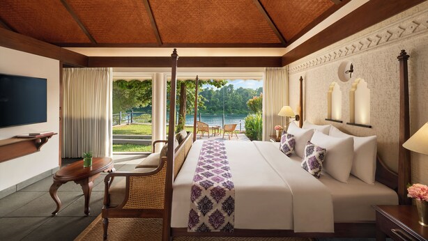 Quarto espaçoso com cama grande, televisão, escrivaninha e vista para um lago.