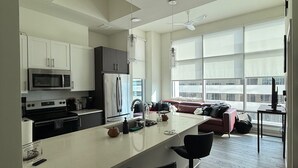 Eine moderne Küche mit einer zentralen Kochinsel, Barhocker und einem Essbereich mit großem Fenster.